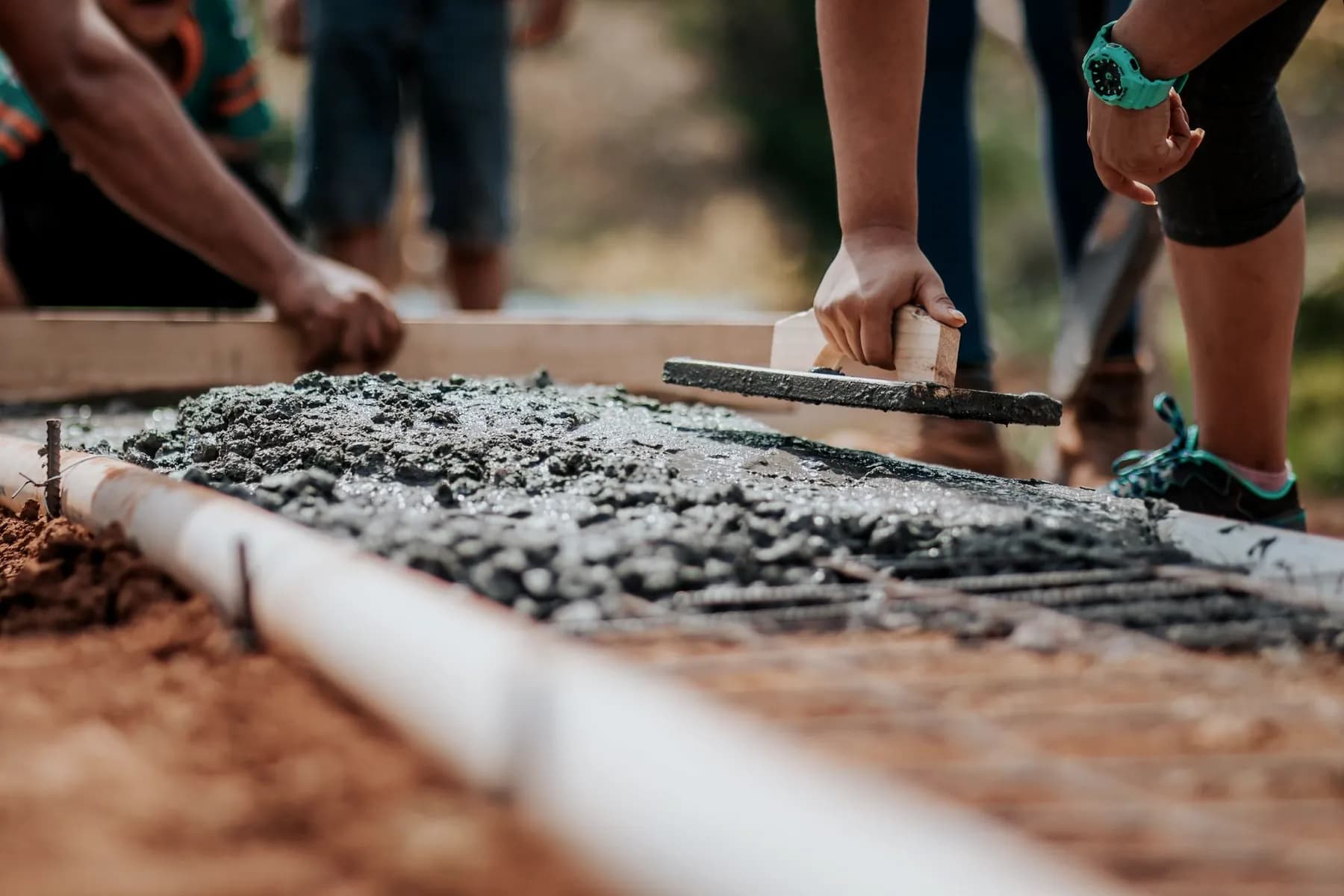 Close-up of hands troweling and finishing wet concrete.
