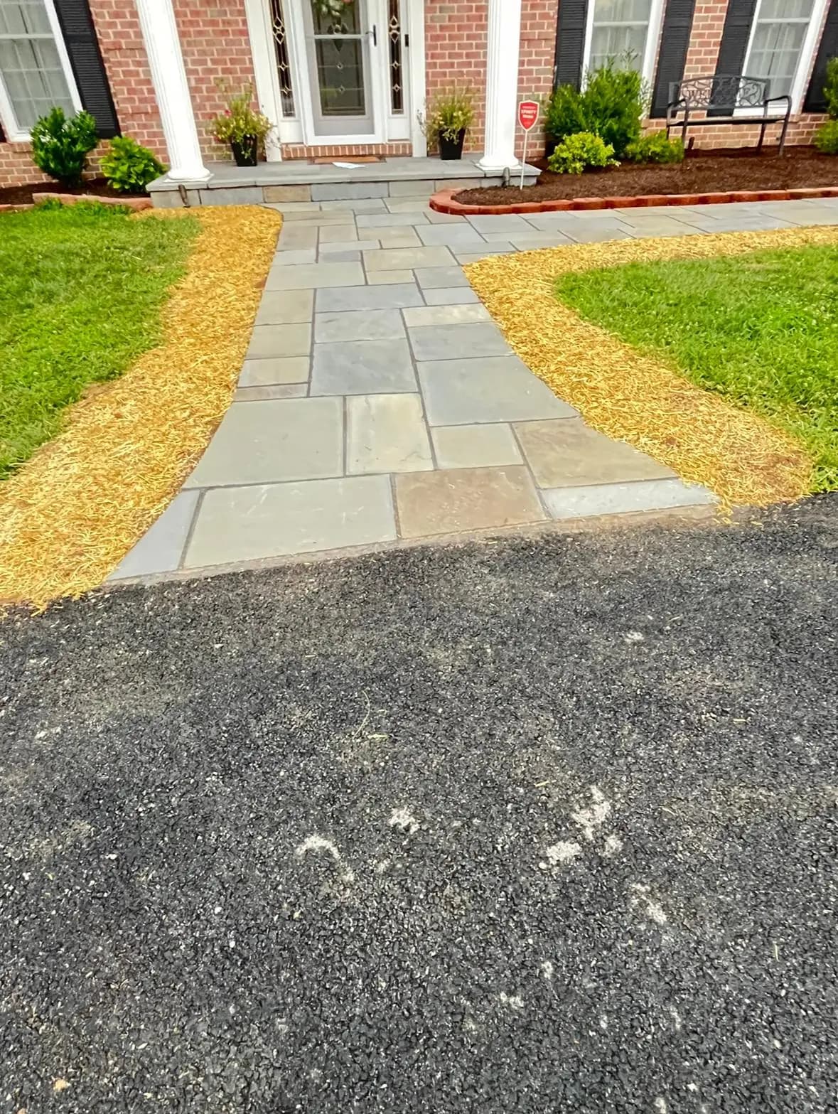 Multi-tone bluestone flagstone walkway with mulch borders leading to a brick colonial entry — Baltimore area, MD.
