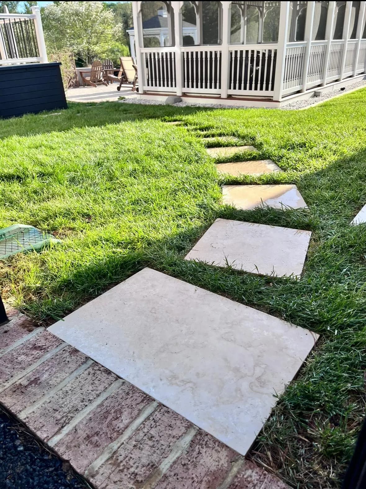 Travertine stepping-stone path set into a manicured lawn near a gazebo — Baltimore area, MD.