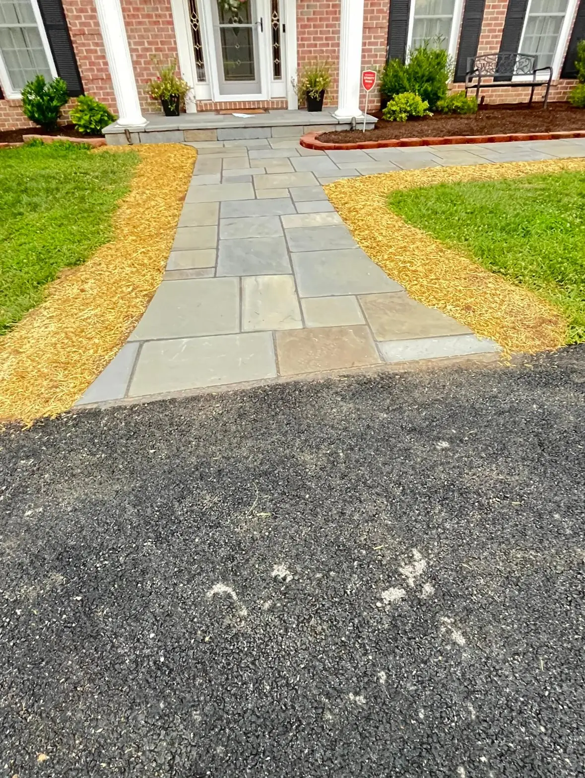 Multi-tone bluestone flagstone walkway with mulch borders leading to a brick colonial entry — Baltimore area, MD.